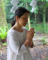 Female Shinto priest prays to calm volcano