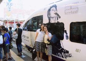 Women pose by train carrying popular singer's image in Nagasaki