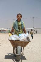 Syrian boy carries packages on cart at refugee camp in Jordan