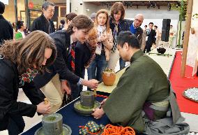 Visitors use hand mills in tea ceremony at Expo Milano Japan Pavilion
