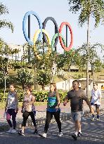 People walk by Olympic rings in Rio de Janeiro park