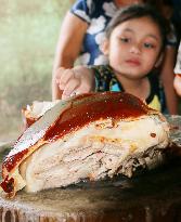 Kid reaches out for lechon roast pig in Cotabato, Philippines