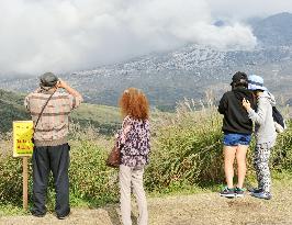 Tourists view smoke rising from Mt. Aso near 'no entry' signboard