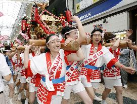 Women carry portable shrines in Osaka parade prior to summer festa