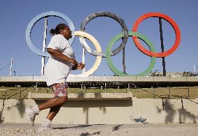 Woman jogs by Olympic rings in Rio de Janeiro park