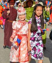 Mongolian girls in traditional costumes march in parade ahead of festival