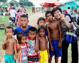 Japanese nurse poses with Cambodian children in Phnom Penh slum