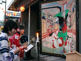 Young women view folding screen painting at west Japan summer festa