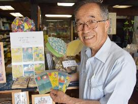 Stationery store owner shows Meiji era postcards