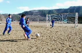 Children play soccer on school ground vacated by temporary homes