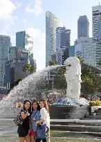 Tourists pose before Singapore landmark statue