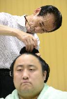 Veteran sumo hairdresser fixes wrestler's topknot