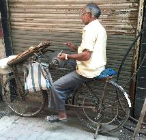 Man sharpening blades using bicycle in India