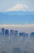 Snow-capped Mt. Fuji behind misty Tokyo skyscrapers