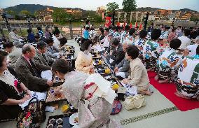 People enjoy cuisine on raised riverbank floor in Kyoto