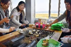 Travelers enjoy barbequed oysters in Fukuoka, southwestern Japan