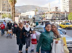 People walk on shopping street in Damascus