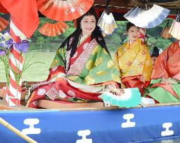 Woman acting as ancient court lady floats fan on Kyoto river