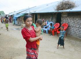 Girl holds baby in Rohingya refugee camp in western Myanmar
