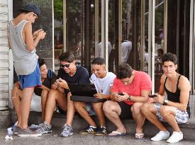 Young Cubans use smartphones on Havana street
