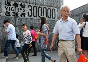 Visitors walk by wall display at Nanjing Massacre Museum