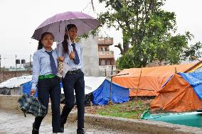 Students walk past quake-hit people's tents in Nepal
