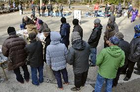 Homeless people wait in line at soup kitchen in Sendai