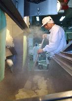 Worker checks steamed rice at Hokkaido "sake" brewery