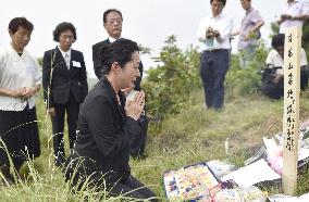 Japanese woman prays in front of grave marker in N. Korea