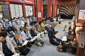 Bus tour participants chant Buddhist sutra at temple
