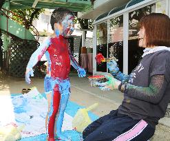Boy puts on paint for "human print" in Osaka Pref.