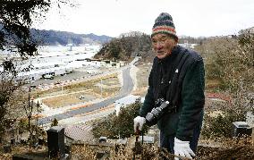 Old man looks at area of home washed away by 2011 tsunami