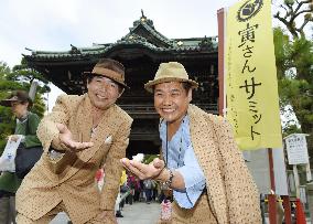 Men in costume of film icon "Tora-san" pose before Tokyo temple