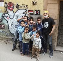 Japanese painter, Egyptian children pose before mural