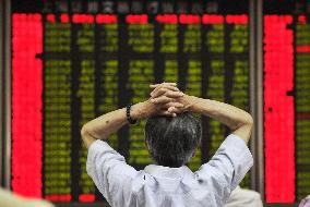 Chinese man looks up at stock price board in Beijing