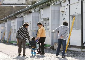 Disaster refugees walk by temporary housing built in schoolyard