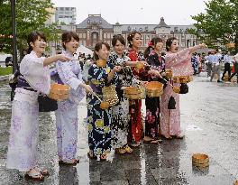 Young women sprinkle water near Tokyo Station at heat-beating event