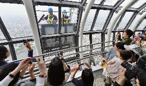 Tourists take pictures of Skytree window cleaners