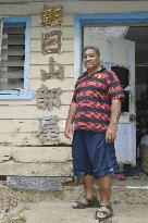 Former Tongan sumo wrestler stands before home on main island