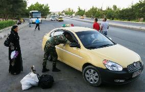 Woman waits for cab near bus terminal in Damascus