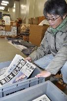 Fukushima museum curator shows newspapers on 2011 disaster
