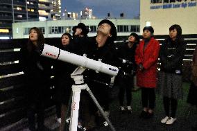 Stargazers look up to sky in middle of neon signs in Osaka