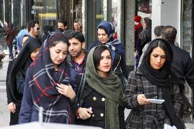 Young Iranian women walk with hair exposed on Tehran street