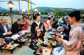 Visitors enjoy cuisine on riverside terrace in Kyoto
