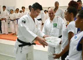 Gold medalist Inoue presents judo uniforms to Brazilian kids