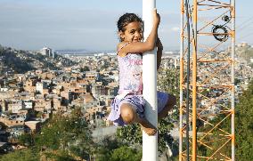 Girl climbing street-light pole in Rio's slum area