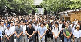 People stand in silence in front of Yasukuni Shrine