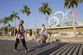 Woman walks by Olympic rings in Rio de Janeiro park