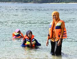Aceh women enjoy sea-bathing in hijabs and life vests