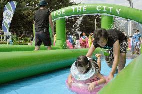 People enjoy water slide set up on street at west Japan spar resort